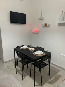 een zwarte tafel met stoelen en een televisie aan de muur bij Casa Vacanza Rosati in Cerignola