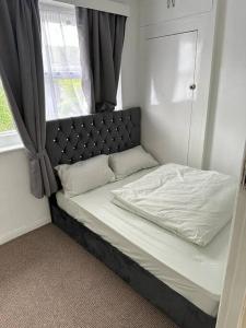 a bed with a black head board and a window at Tomla Inn-3 Beds House - 6 people sleeps-Greenwich Holiday Short Let in Plumstead +3 photos
