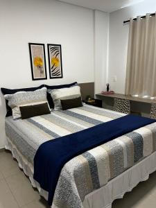 a bedroom with a large bed with blue and white sheets at Studio no West Fit Mossoró Alto Padrão in Mossoró