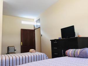 a bedroom with two beds and a tv and a dresser at Bonita casa acogedora in Cochabamba