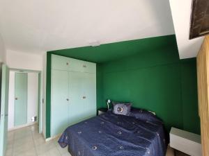 a bedroom with a green wall and a bed at Temporario 3B in Resistencia