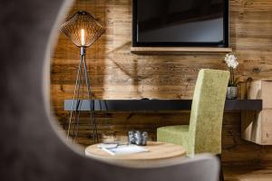 a room with a table and a chair and a television at Hotel Erika in Braies