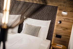 a bedroom with a bed with white sheets and pillows at Hotel Erika in Braies