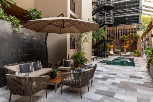 a patio with chairs and an umbrella and a pool at Dominion Polanco in Mexico City