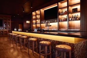 a bar with stools in a room with alcohol at The Scarlet, Lincoln, a Tribute Portfolio Hotel in Lincoln