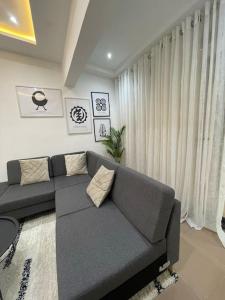 ein Wohnzimmer mit einem grauen Sofa vor einem Fenster in der Unterkunft Modern Family House with 2 bedrooms + Free Parking in Ashaiman