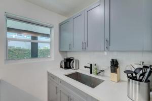 a kitchen with white cabinets and a sink and a window at SuaveMauve Las Olas Beach in Fort Lauderdale