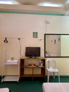 Zimmer mit einem TV, einem Spiegel und einem Stuhl in der Unterkunft Anda Seabreeze Pension Haus in Anda
