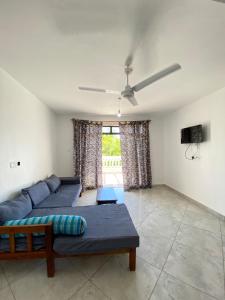 sala de estar con 2 sofás azules y ventilador de techo en Silent Palms Villa, en Galu