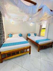 2 camas en una habitación con paredes y ventanas blancas en Silent Palms Villa, en Galu