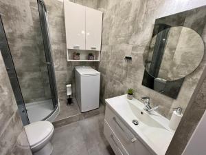 W łazience znajduje się umywalka, toaleta i lustro. w obiekcie Apartamenty KoktajLOVE w Kielcach