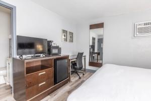 a hotel room with a bed and a desk with a television at Butler Inn in Oxford