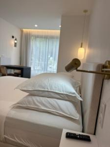- une chambre avec un lit doté de draps et d'oreillers blancs dans l'établissement Le cap dagde, au Cap d'Agde