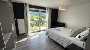 ein Schlafzimmer mit einem Bett und einem großen Fenster in der Unterkunft Villa 4 Saisons, avec piscine chauffée et jacuzzi in Gérardmer