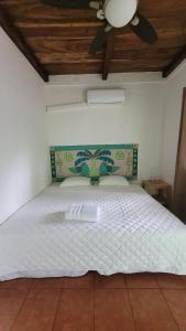 a bedroom with a white bed with a ceiling fan at Hotel Zelen in Tamanique