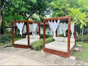 Hotel Zelen في Tamanique: سريرين مع ملاءات بيضاء وستائر