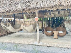 a hammock and hammocks in a straw hut at Hotel Zelen in Tamanique