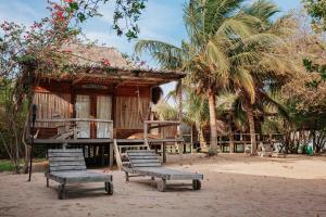 two chairs sitting in front of a house with palm trees at Awatawaa Ecolodge in La Punta de los Remedios