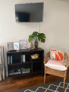 a living room with a chair and a book shelf at Heddfan - Peaceful Studio 5 mins from Stunning Llanbedrog Beach in Pwllheli
