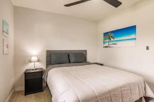 a white bedroom with a bed and a lamp at Cottage Near Beach, Heated Pool, Full Kitchen! in Fort Myers