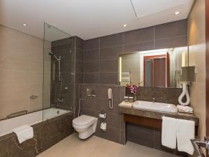 a bathroom with a sink and a toilet and a bath tub at Flora Al Barsha Hotel At The Mall in Dubai