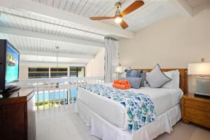 a bedroom with a bed and a tv and a balcony at K B M Resorts Napili Villa C31 Ocean Front 2BDRM in Kapalua