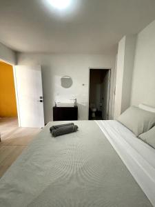 1 dormitorio con 1 cama blanca grande y baño en Nina´s - Juan Santamaria, en Alajuela