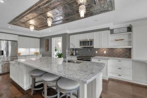 a kitchen with white cabinets and a large island with bar stools at Amazing Luxury 6BR - Pool - 30min to Niagara Falls in Hamilton
