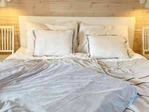 uma cama com lençóis brancos e almofadas em 4 person holiday home in SKURUP em Skurup