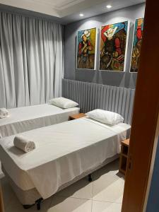 Condominio Barretos Thermas Park - Condohotel 1242 في باريتوس: سريرين في غرفة بها لوحات على الحائط