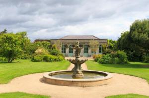 une fontaine au milieu d'un jardin avec un bâtiment dans l'établissement Marlay Grange Luxury Guest House, à Dublin