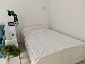 Una cama blanca en una habitación blanca con plantas en Ruhige Wohnung am Rande des Naturschutzgebietes en Ingelheim am Rhein