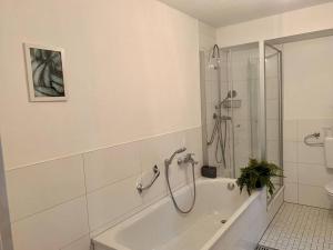 a white bathroom with a shower and a bath tub at Ruhige Wohnung am Rande des Naturschutzgebietes in Ingelheim am Rhein