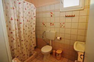 a bathroom with a toilet and a shower curtain at Countryside Cottage with Garden & Lake View in Peraía