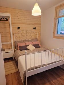 1 dormitorio con 1 cama con pared de madera en Domek Szyszka, en Okuninka