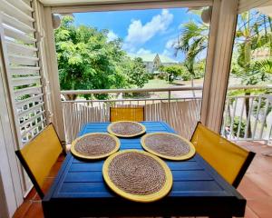 a blue table with four plates on it on a porch at VILLA Ti Paradis ANSE DES ROCHERS in Saint-François