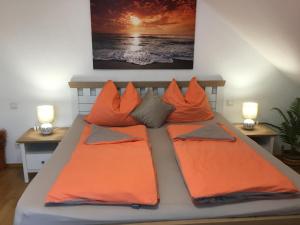 ein Bett mit orangefarbenen Kissen und zwei Lampen darauf in der Unterkunft Apartment Eichwald in Sexau