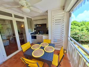 a blue table with yellow chairs on a balcony at VILLA Ti Paradis ANSE DES ROCHERS in Saint-François