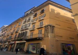 a tall building on a street with people walking past it at Casa del Vicolo, nel cuore della Pavia storica in Pavia