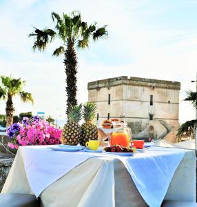 una mesa con fruta y bebidas con una palmera en Acquamarina B&b, en Porto Cesareo