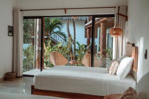 a bedroom with a white bed and a large window at AmarBacalar in Bacalar