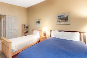 a bedroom with two beds and a blue blanket at Creekside Condo in Girdwood