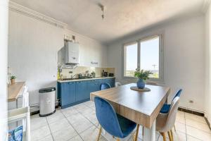 cocina con mesa de madera y sillas azules en L'élégant Zola, en Villeurbanne