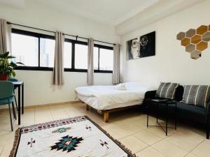 a bedroom with a bed and a couch and windows at Lev Florentin Apartments - Montefiore TLV in Tel Aviv