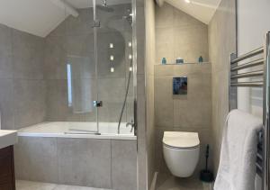 a bathroom with a shower and a toilet and a tub at April Cottage in Brixham