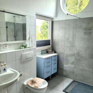 ein Bad mit einem Waschbecken, einem WC und einem Fenster in der Unterkunft Green Hill in Siegburg