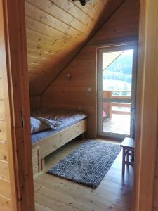 a bedroom in a log cabin with a bed and a window at Beskidzkie Zacisze in Uście Gorlickie
