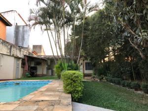 een achtertuin met een zwembad en een huis bij Open House Timboré in Sao Paulo