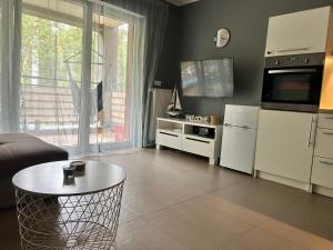 a living room with a table and a kitchen at Apartament Przy Lesie in Międzywodzie