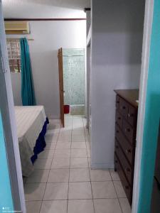 a bedroom with a bed and a dresser and a bathroom at The Couples Inn in Montego Bay